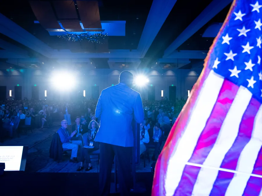 Conference speaker on stage with American flag — event photography Austin TX